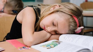 Lernen im Schlaf: Ein Mädchen hat den Kampf gegen die Müdigkeit verloren und ist während des Unterrichts eingeschlafen.