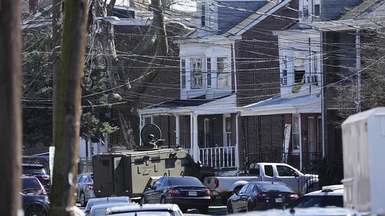 Polizisten umstellen ein Haus. Ein Verdächtiger hatte sich in dem Haus verbarrikadiert und Geiseln genommen, nachdem er in einem Vorort von Philadelphia drei Menschen erschossen hatte. Foto: Matt Rourke/AP/dpa