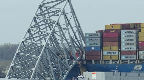 Ein Containerschiff liegt vor dem Wrack der Francis Scott Key Bridge. Das Schiff rammte einen Pfeiler der vierspurigen Brücke und brachte sie damit weitgehend zum Einsturz. Foto: Matt Rourke/AP/dpa