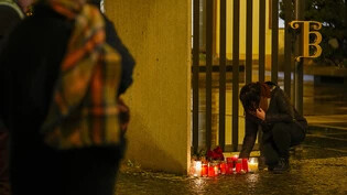 Eine Person entzündet Kerzen vor dem Gebäude der Philosophischen Fakultät der Karls-Universität in der Prager Innenstadt. Foto: Petr David Josek/AP/dpa