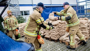 Einsatzkräfte der Feuerwehr geben auf einem Parkplatz zahlreiche Sandsäcke an die Anwohner im Bereich der Hunte am Achterdiek aus. Die Hochwasserlage bleibt in vielen Regionen Niedersachsens angespannt. Foto: Hauke-Christian Dittrich/dpa